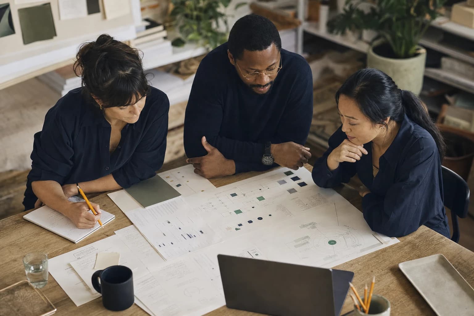 Three colleagues reviewing a system map around a table